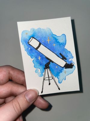 Maggie's hand holding a trading-card sized artwork of a telescope done in ink and watercolor. It's lit with flash to show glitter in the watercolor background and gold ink stars. 